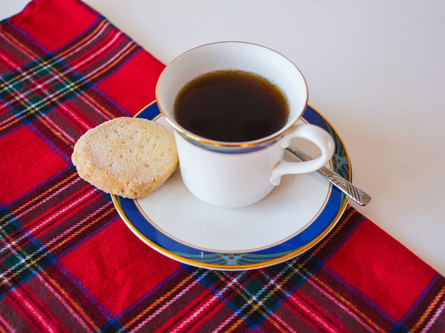 Highlanders Traditional Shortbread Traditional Shortbread next to a cup of coffee, on a Scottish tartan fabric
